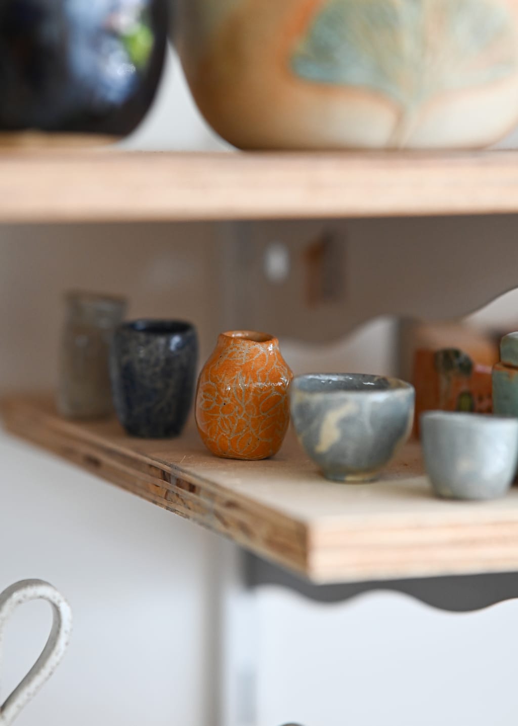 Prateleiras do ateliê cheias de peças de cerâmica esmaltadas