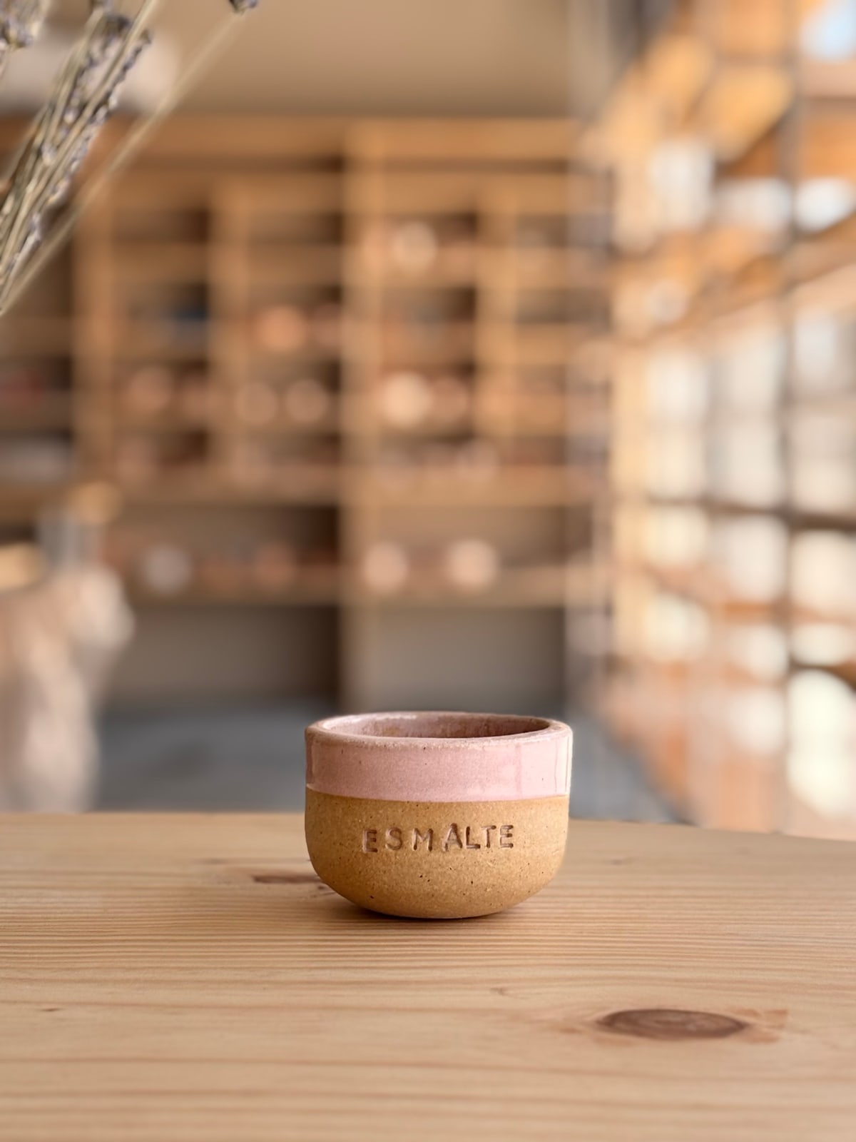 Uma cumbuca com a borda esmaltada em rosa e a base de argila aparente, com a palavra ESMALTE gravada
